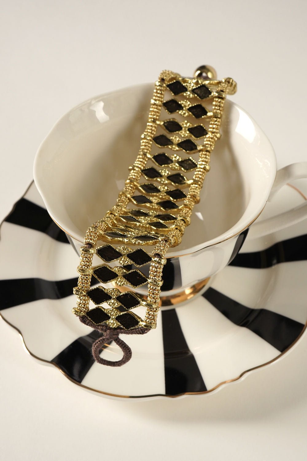 Detalle Vajilla Brazalete Dorado Con Diseño De Rombos Negros Cristina Oria