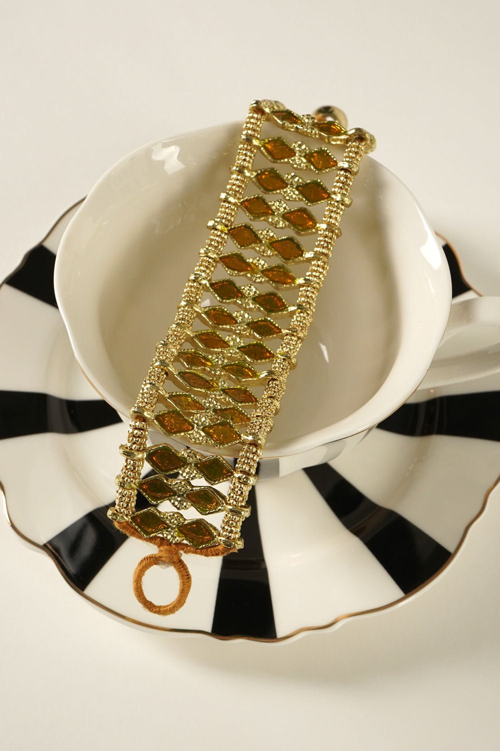Detalle Vajilla Brazalete Dorado Con Diseño De Rombos Naranjas Cristina Oria