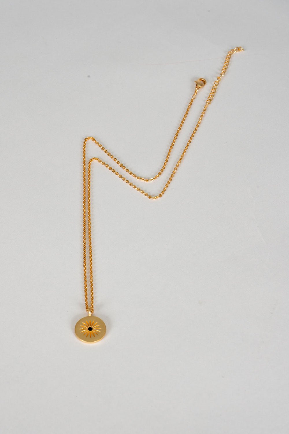 Colar dourado com pendente redondo de sol e zircónia negra