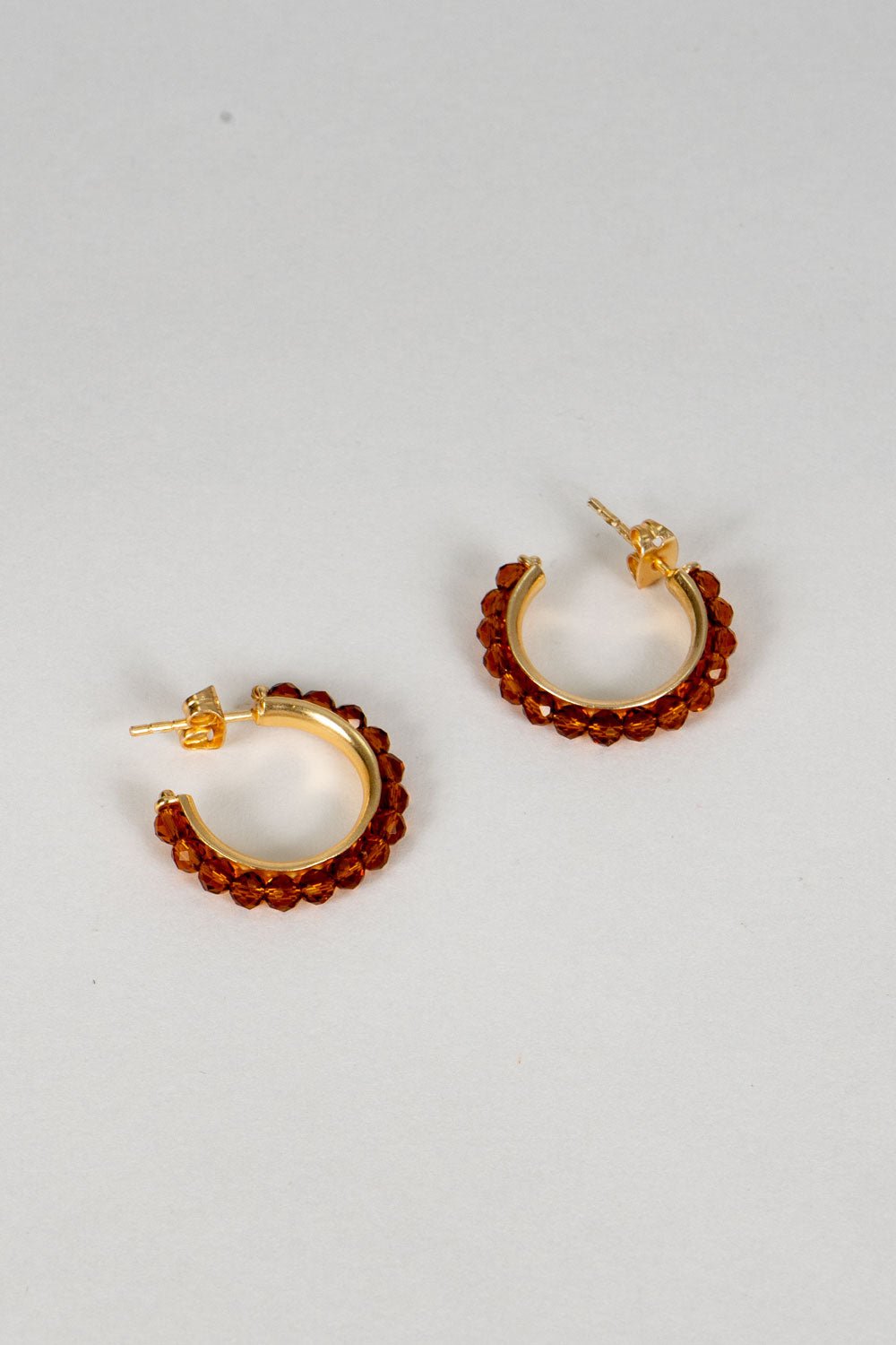 Brincos dourados com design de argolas e pedras âmbar